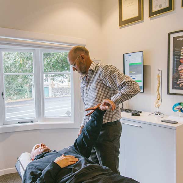 mt eden chiropractor using the applied kinesiology technique on a patient lying on a table. Window in background