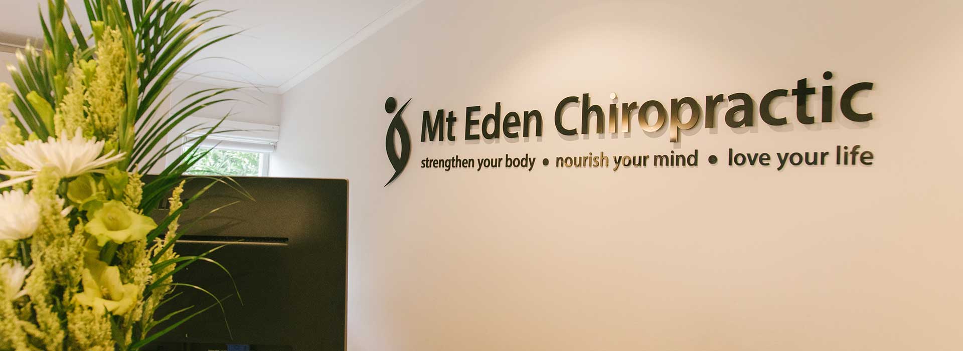 Close up of Mt. Eden Chiropractic company slogan on white wall